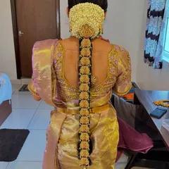A stunning traditional bridal hairstyle from the back, featuring a long braid adorned with jasmine flowers and gold accessories.