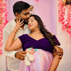 An intimate moment between expectant parents. The soft lighting and floral background create a gentle and loving atmosphere, perfect for a maternity portrait.