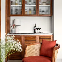 This compact bar unit is a beautiful blend of modern and traditional design, with louvered wooden shutters, a marble top, and fluted glass cabinets.