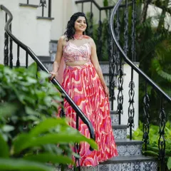 The bride posing on a staircase, her vibrant Haldi outfit in full view. The hairstyle is playful and pretty, perfect for the occasion.