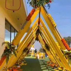 I design classic and welcoming entrances for Haldi ceremonies. This beautiful walkway tunnel is created with bright yellow drapes and traditional orange and yellow marigold flower arrangements, setting a perfect festive tone.