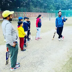 A coach addresses a group of young players during an evening session. These team talks are important for discussing strategy, setting goals, and motivating the players.