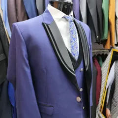 A royal blue three-piece suit designed for a groom or for party wear. The black velvet detailing on the lapels adds a touch of luxury and contrast, making it a standout choice.