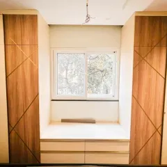 We used a combination of wood-tone shutters with metal inlays and matte cream panels for this twin wardrobe design, creating a look that is both luxurious and inviting.