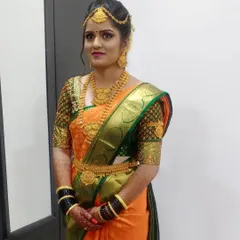 A full view of this bride's Muhurtham look. The orange Kanjeevaram is draped perfectly to show off the intricate blouse work, and the makeup is balanced to complement the vibrant colors.