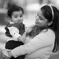 A mother holds her baby close in this tender monochrome portrait. The lack of color draws all attention to the loving expression on her face and the baby's curious glance.
