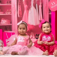 Double the fun with twin baby girls dressed as Barbie. This shot captures their adorable interaction in the fully pink, sparkly studio setup.