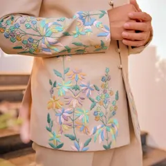 The soul of our work is in the details. This close-up reveals the delicate, multi-colored floral embroidery on one of our custom bandhgala jackets. Each thread is placed with precision by our karigars to create a design that feels both opulent and personal.