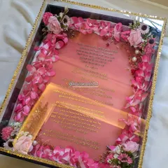 A wedding day is special, so the invitation should be too. This is a custom resin wedding invitation, or Kankotri, with the text in Gujarati font using a metal sticker. The 12x16 inch resin piece is presented in a beautiful box framed with artificial flowers.