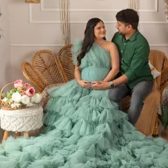 A beautiful couple portrait in our boho-chic studio. The mom-to-be is stunning in a sea-green ruffled gown, seated on a stylish rattan sofa.