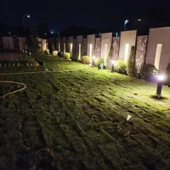 This is the final look of a large-scale lawn renovation, illuminated by strategically placed garden lighting. We use premium natural grass turf to create expansive, healthy lawns for farmhouses and commercial properties, ensuring a stunning result day or night.