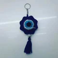 This is our flower-shaped evil eye or nazar battu keychain, designed to bring good vibes. Made with deep blue yarn and finished with a tassel, it's a beautiful and meaningful charm for your keys or to hang in your car.