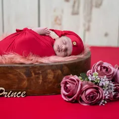 A simple, powerful portrait of a newborn prince. We used a rich red swaddle and a heart-shaped wooden bowl to create this classic, loving image.
