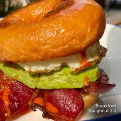 This is the Breakfast Doughnut 2.0 from our Padaria Prazeres pop-up. It's a perfect example of the playful yet delicious food I love to showcase: a maple-glazed doughnut with a fried egg, crispy bacon, avocado, and hot sauce.