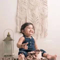The aftermath of a successful cake smash. This little one's joyful, messy face in a boho-themed setup is a picture of pure delight.