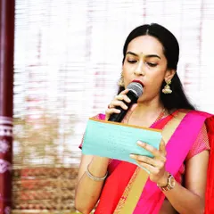Focused and ready, reading my notes before an announcement. This was for a traditional South Indian event where I hosted in a classic pink and red saree, ensuring the program ran smoothly.