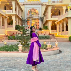A full shot of my custom-made purple Anarkali suit from a homegrown brand, set against a beautiful palace backdrop. The vibrant purple with the contrasting pink dupatta makes for a perfect wedding guest look.