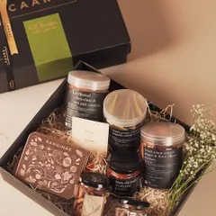 An overhead view of our CAARA x Bruijn collaboration hamper. This gift box is filled with a delightful assortment of sun-dried tomato pesto, artisanal cookies, and premium nuts from Bruijn.
