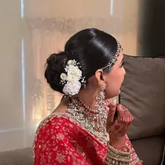 This classic bridal bun is adorned with fresh white carnations and baby's breath. It's a timeless choice that perfectly complements a traditional red lehenga for the Pheras.