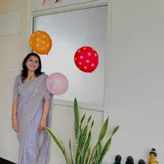 Standing proudly by our studio door during our 2nd-anniversary celebration. The sign says, "Yoga doesn't take time, it gives time," a philosophy we truly live by.