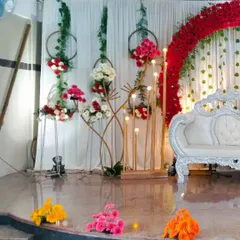 This is a classic wedding reception stage I designed. It features a grand floral arch with red roses, elegant white drapery, and warm lighting to create a romantic and timeless setting for the couple.