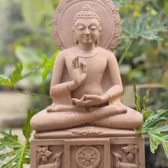 This serene Gautama Buddha statue, hand-carved from pink sandstone, is shown in the dharmachakra pravartana mudrā, or the teaching posture. It is a perfect sculpture for creating a peaceful atmosphere in any indoor or garden space.