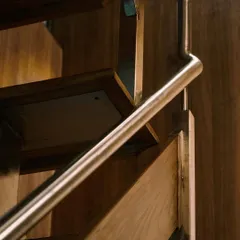 A close-up of the staircase reveals the precise joinery between the wooden treads and the sleek metal handrail, a testament to our focus on high-quality craftsmanship.