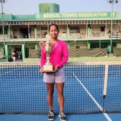 Shruti Gupta stands proudly on the court with her Women's Singles championship trophy at the Bengal Tennis Association.