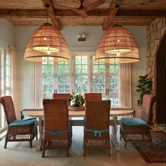 In this rustic dining room, we used an arched entry of Jaisalmer stone and a coffered wood ceiling to evoke a bygone era. The 9-foot dining table and oversized woven jute chandeliers complete the grand, yet warm, setting.