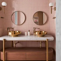 In this kid's bathroom, I designed a custom vanity with a marble top and brass legs to hold two statement golden sinks. The playful pink tile is balanced by the sophisticated materials, creating a space that is both fun and elegant.