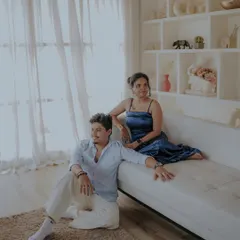 A relaxed and stylish portrait from an indoor pre-wedding shoot. The clean, white aesthetic of the studio set creates a modern and chic vibe.