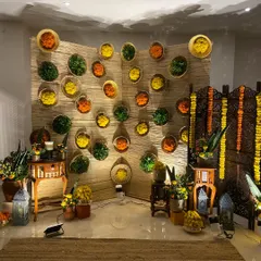 A "Taste of India" themed setup for a Diwali party. The backdrop is made of bamboo mats adorned with baskets of colorful marigolds, and the space is decorated with traditional lanterns and screens.