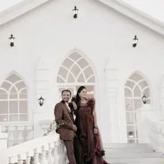 An elegant couple poses on the steps of a pristine white chapel-like building, creating a classic and timeless pre-wedding photo.