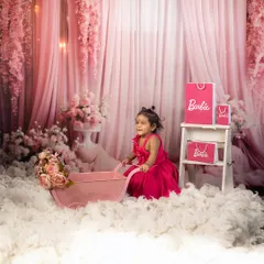 A Barbie world, but make it mommy-approved. This dreamy setup with pink floral curtains, fluffy clouds, and Barbie accessories is perfect for creating magical portraits of your little girl.