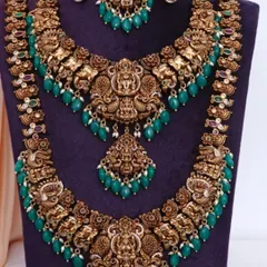 A close-up of a beautiful Nakshi work haram set. The detailed craftsmanship with Goddess Lakshmi and peacock motifs, paired with green beads, makes it a statement piece.