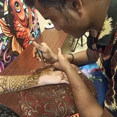 Here I am, focused on the details. This shot shows me applying an intricate pattern on a client's arm. I work with precision and patience to ensure every line is perfect.