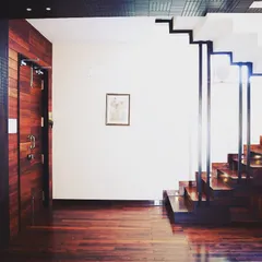 For the Overseas Traders office, we used reclaimed wood from the client's musical instrument business. This view shows the rich wooden flooring and a staircase with clean, modern lines, demonstrating a commitment to sustainability and craftsmanship.