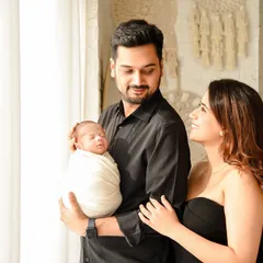 A candid moment from a newborn family session. The parents gaze lovingly at their sleeping baby, a simple and powerful image of adoration and connection.