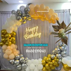 A full ring balloon arch in elegant gold, silver, and peach tones. This setup includes a floral accent and a "Happy Birthday" neon sign, creating a sophisticated photo corner.