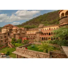 This photograph captures the multi-level architecture and verdant courtyards of the Neemrana property, showing the intricate relationship between the structure and its natural surroundings.