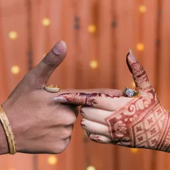 A creative shot of the couple's hands, showcasing their wedding rings and the bride's detailed henna.