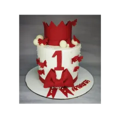 A bold and beautiful first birthday cake in red and white. This chocolate truffle Ferrero Rocher cake is decorated with a crown, a large bow, and butterflies.
