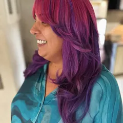 The smile says it all. This pink and violet color with curtain bangs is all about expressing personality and having fun with your hair.