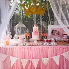 A close-up of a princess-themed dessert table. The pink tulle skirt, gold crown, and perfectly coordinated cake and treats create a sweet and royal display.