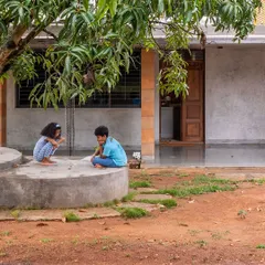 The farmhouse was designed to be inconspicuous and uncomplicated, nestled among the mango trees. The material palette of raw cement, earth, and stone borrows shades from the surroundings, rooting the architecture in its place.