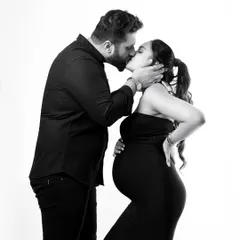 A moment of pure love and affection. This black and white maternity photo captures a tender kiss, focusing on the couple's emotion and the beautiful silhouette of the baby bump.