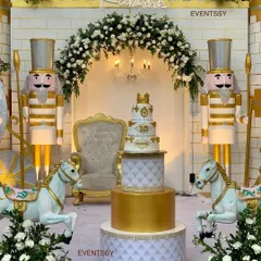 A close-up of the cake display area from the royal prince party. The multi-tiered cake sits center stage, flanked by carousel horses and guarded by life-sized nutcracker figures, creating a truly regal scene.