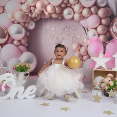 A princess on her throne for her first birthday! This beautiful setup with a pink balloon arch and the word "One" creates a magical setting to celebrate this major milestone.