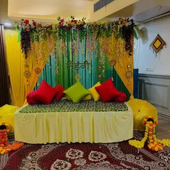 This is a classic mehndi seating arrangement with a green and yellow backdrop. I used hanging floral strings, colorful cushions, and Rajasthani umbrellas to complete the traditional look.