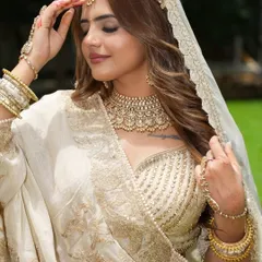 The epitome of grace. This ivory and gold ensemble features a stunning Kundan choker, matching matha patti, and a full set of bangles, creating a look of pure elegance for any grand celebration.